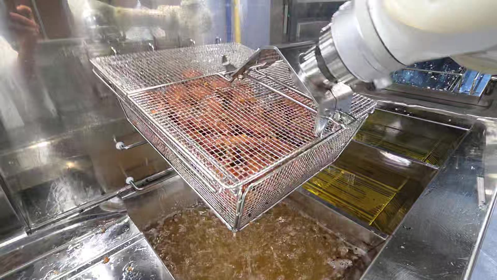 The robot lifting a basket of fried chicken out of the oil